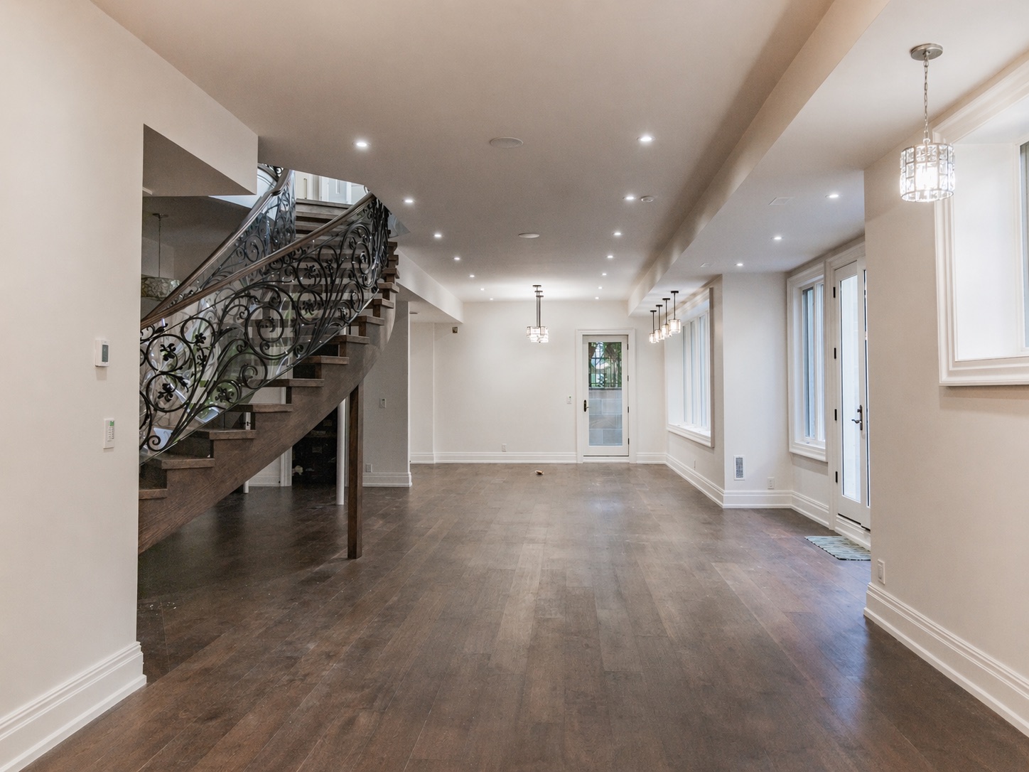 Finished basement with elegant staircase, plank flooring, and clean painted walls