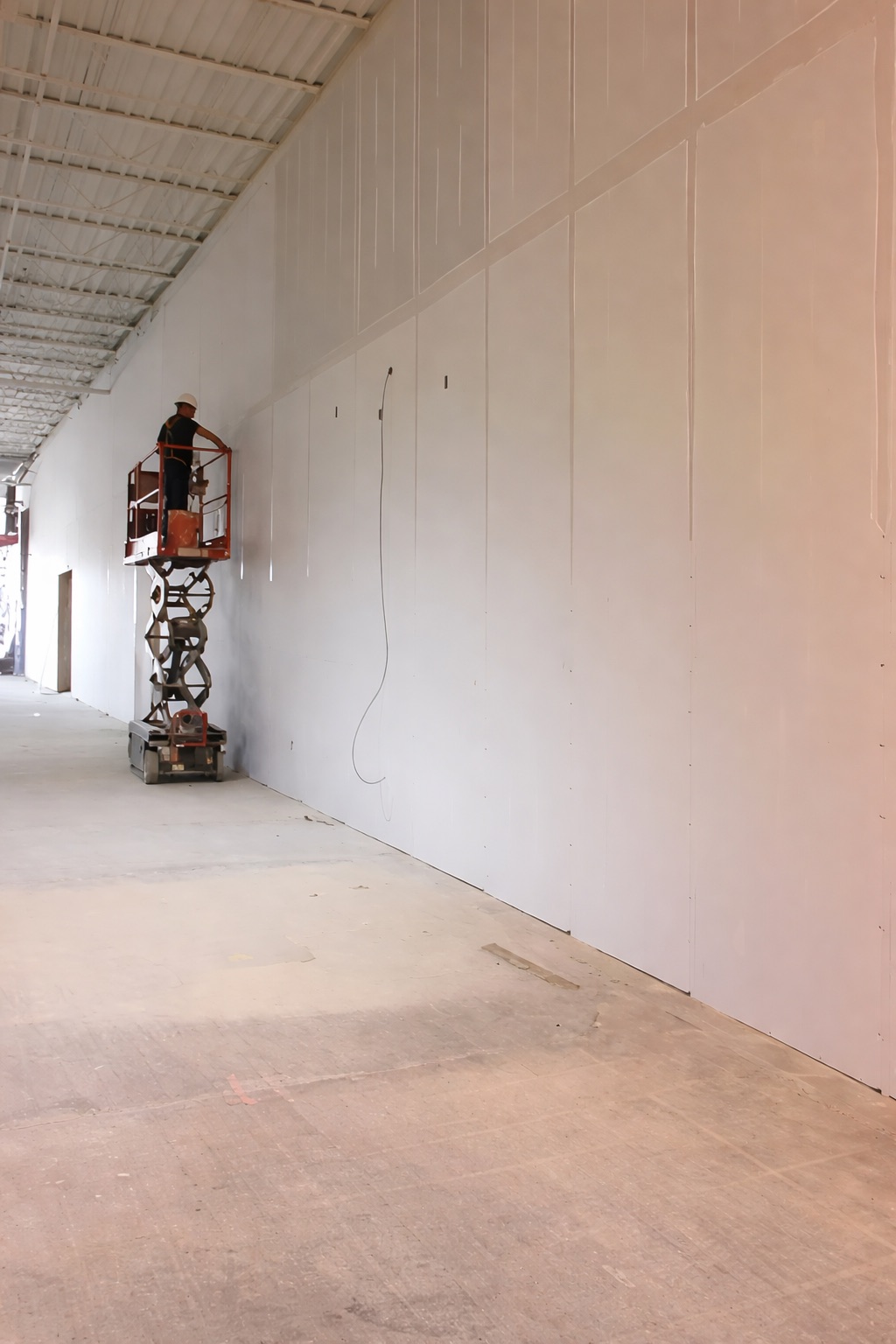 Commercial drywall boarding on scissor lift with large-format panels in Toronto