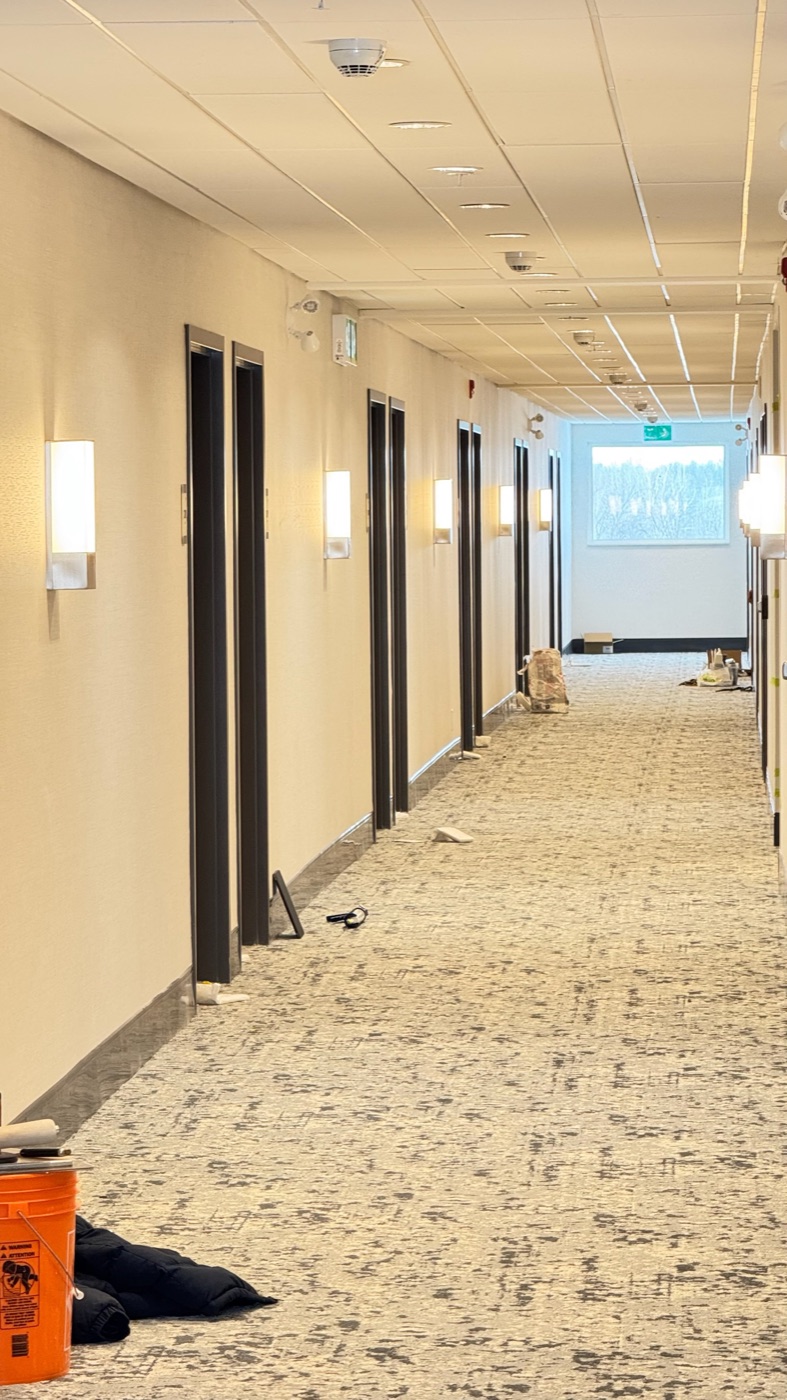 Finished hotel guest corridor with wall sconces