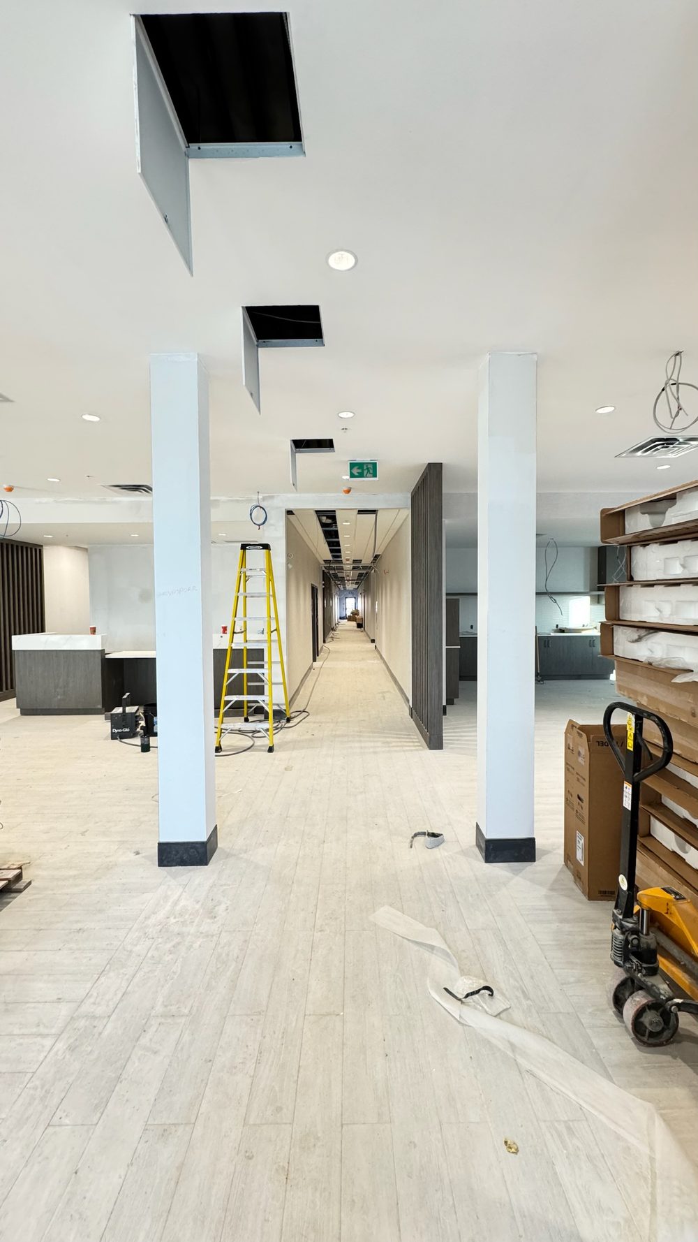 Drywall ceiling with recessed bulkheads and columns in a hotel lobby, ladder up
