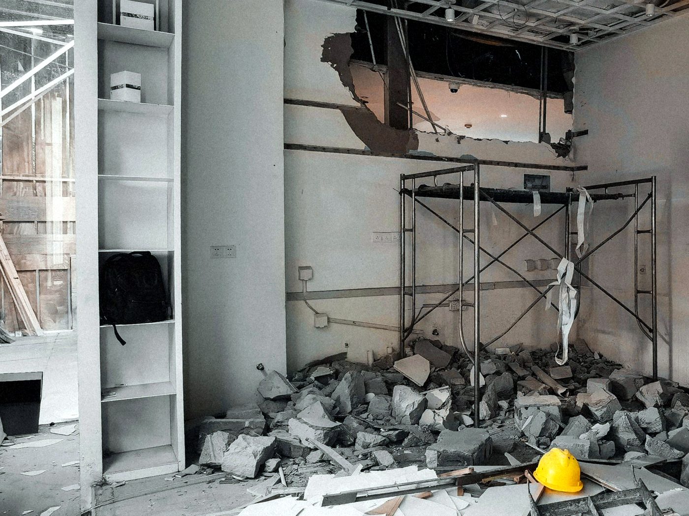 Retail unit partway through a strip-out, with the ceiling tiles out and broken drywall and block on the floor
