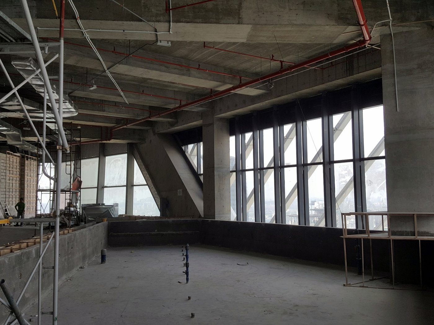 Commercial floor stripped back to the concrete shell, with scaffolding and exposed sprinkler pipe