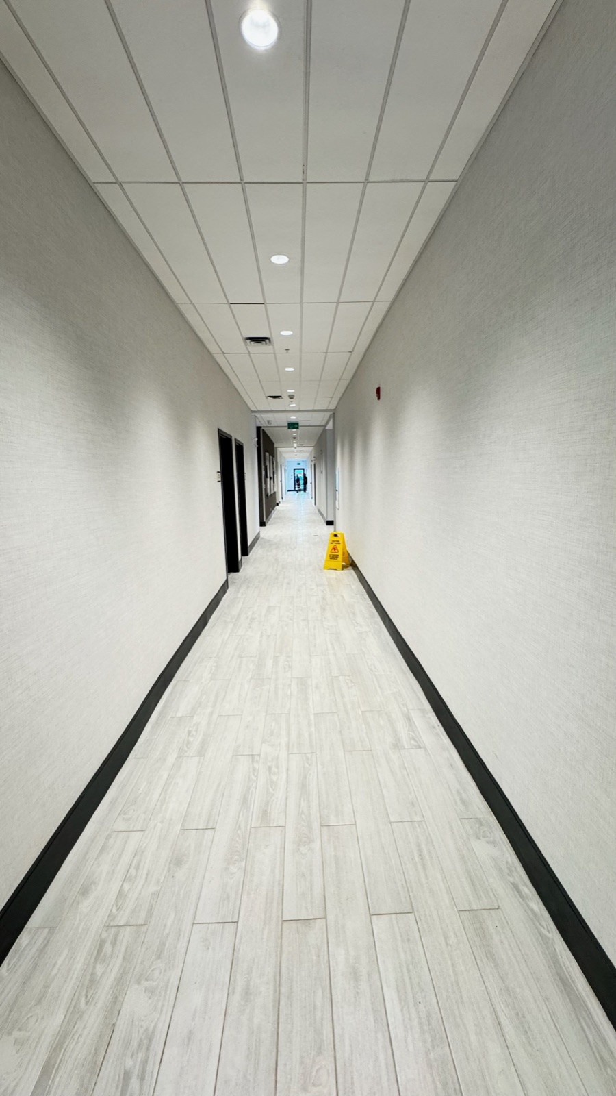Completed hotel corridor with finished walls, flooring, doors, and ceiling grid