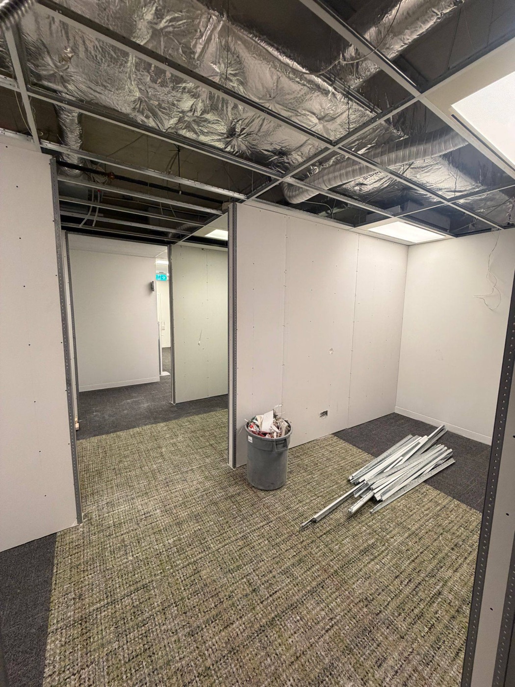 Office partition framing meeting a T-bar grid